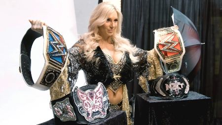 Charlotte Flair poses with all her titles.